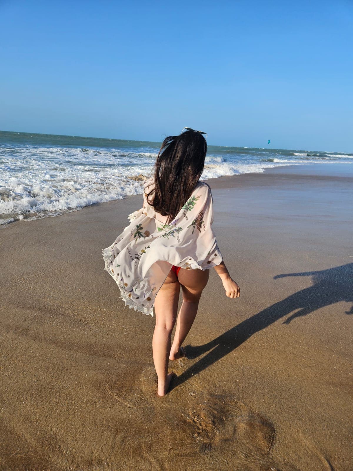 caminhando com o xale ao vento, na beira do mar