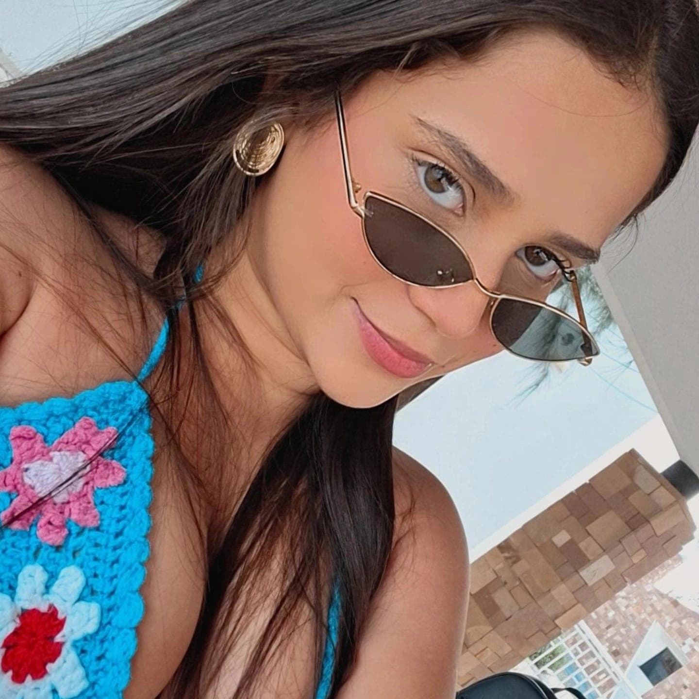 top de crochê, óculos escuros, sorriso discreto